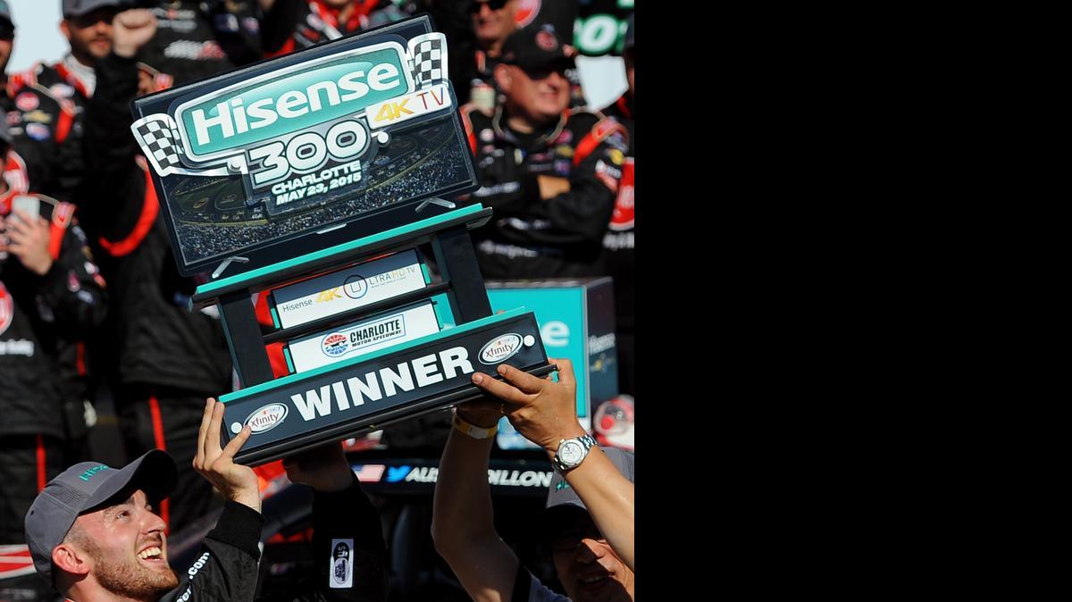 
NASCAR Xfinity Series driver Austin Dillon, left, smiles as he is assisted in lifting the the Hisense 300 trophy after winning the race at Charlotte Motor Speedway in Concord, Saturday, May 23, 2015.

