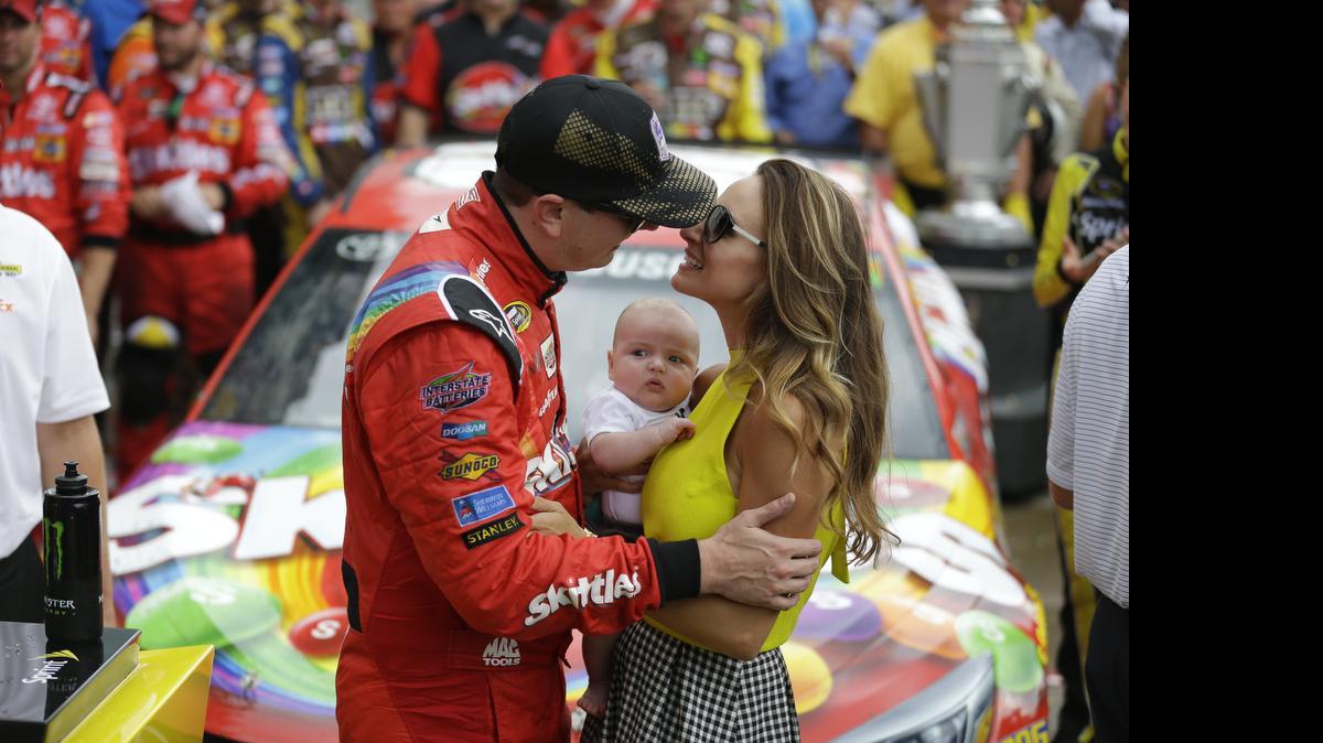 
Sprint Cup Series driver Kyle Busch (18) kisses his wife Samantha as his son Brexton looks on as he celebrates after winning the NASCAR Brickyard 400 auto race at Indianapolis Motor Speedway in Indianapolis, Sunday, July 26, 2015.
