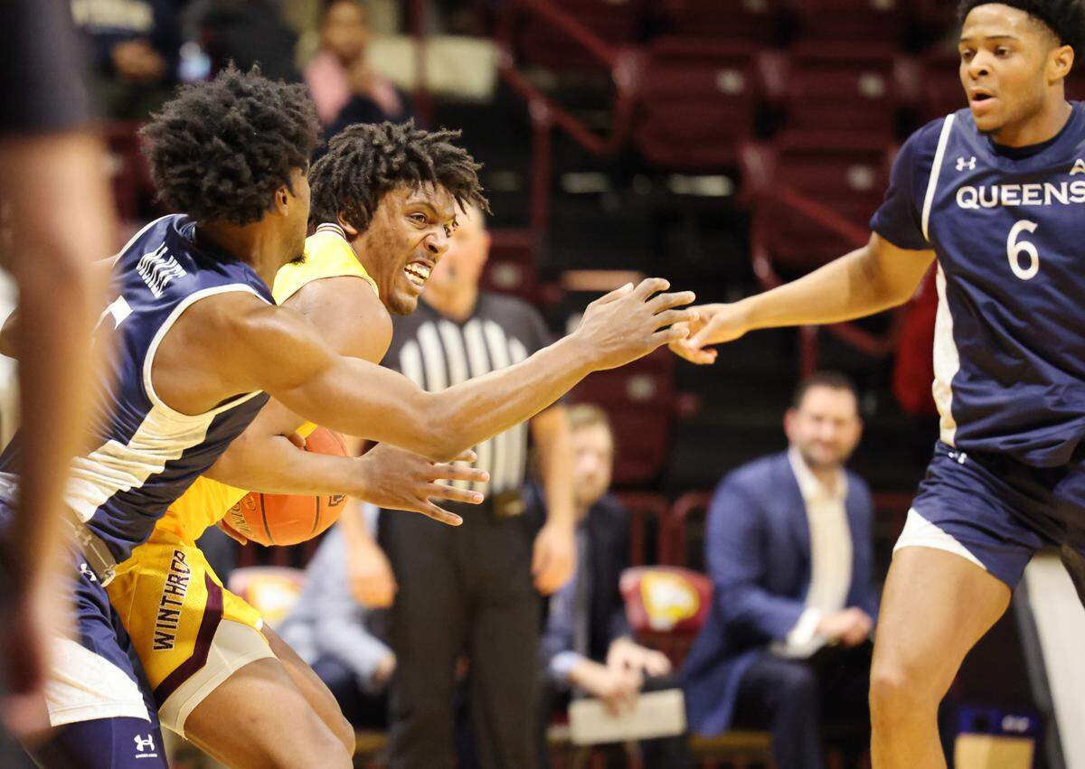 Winthrop’s K.J. Doucet looks for an opening around Queens’ A.J. McKee, left, and B.J. McLaurin