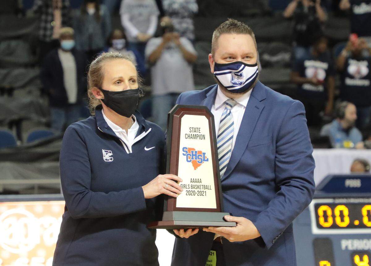 Clover High School girls basketball coach Sherer Hopkins accepts a state championship trophy Saturday after the team wins the game 40-38 in Aiken.