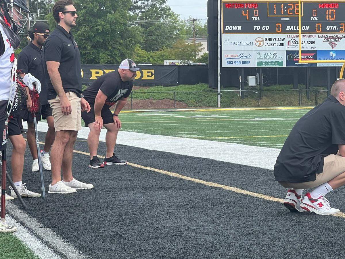 Nation Ford boys’ lacrosse head coach Cory Turner (hands on knees, white and black hat) watches his team in the SCHSL 5A State Championship Game against Wando on April 27.
