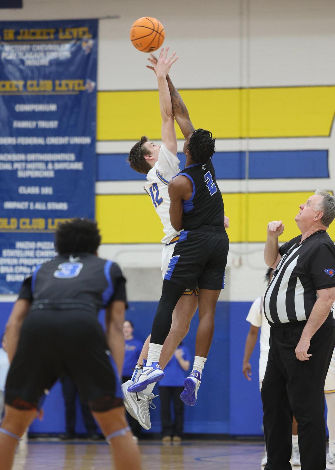 Fort Mill’s Wallace Campbell (12) and Indian Land’s Sequel Patterson tip off the basketball during the start of the rivalry game in Fort Mill.