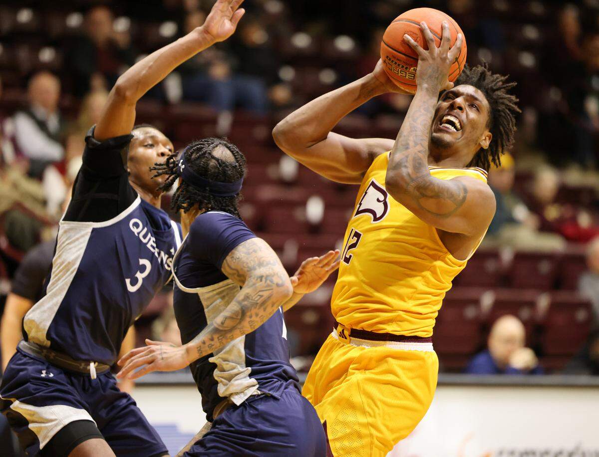 Winthrop’s K.J. Doucet takes the shot around Queens’ Kalib Mathews (3) and Jacobi Sebock in a 2023 game.