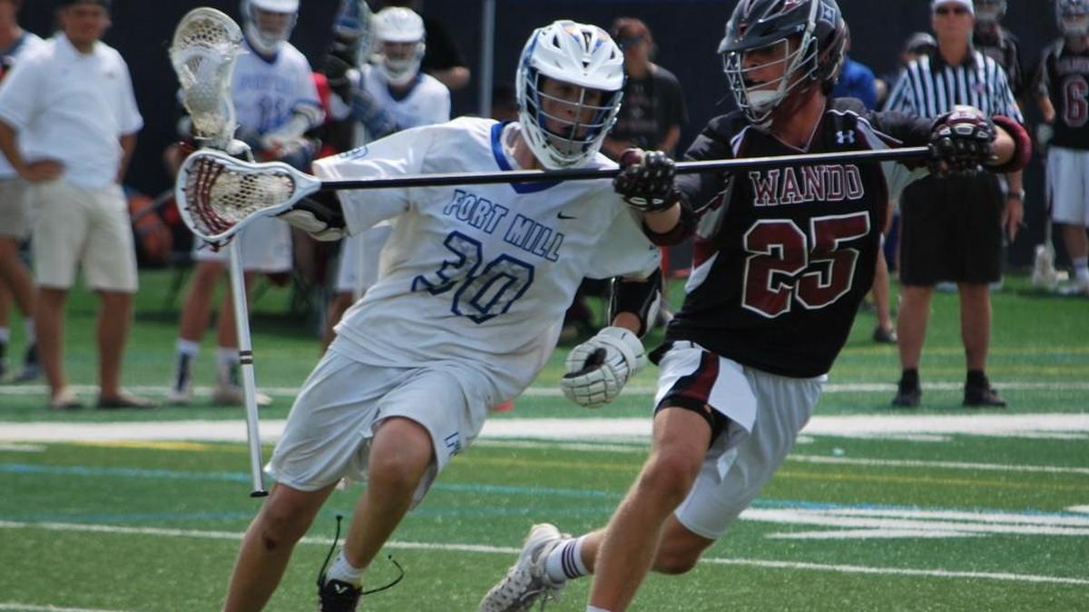 Fort Mill’s Trenton Wylie, left, tries to run past Wando’s Thomas Gribben during Saturday’s 4A boys state lacrosse championship at Chapin High School.