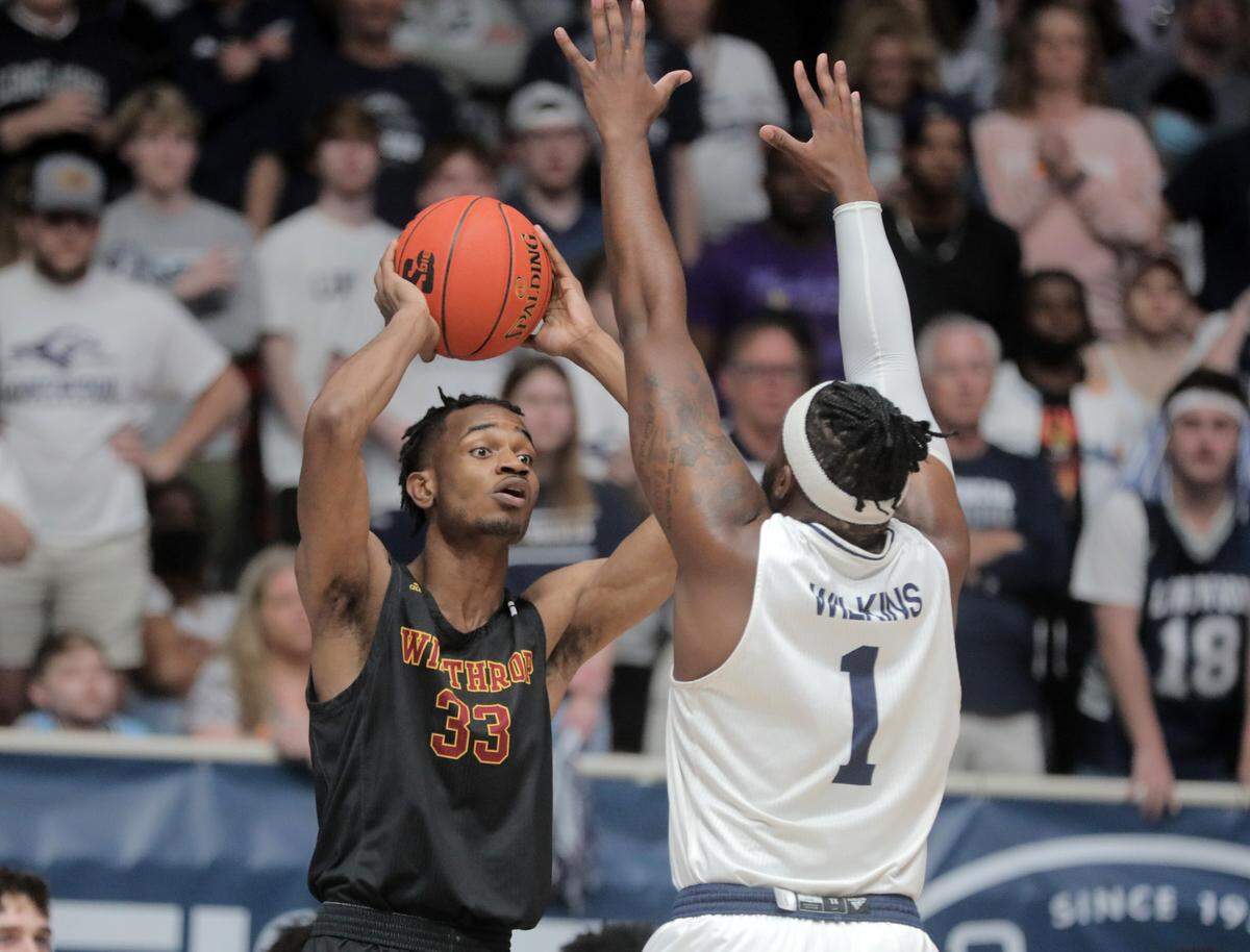 Winthrop’s Chase Claxton looks for an opening over Longwood’s Isaiah Wilkins Sunday at the Big South Championship game.