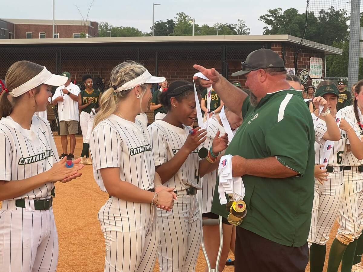 Catawba Ridge head coach Michael Kidd dons a medal on junior right fielder Aloni Hogans.