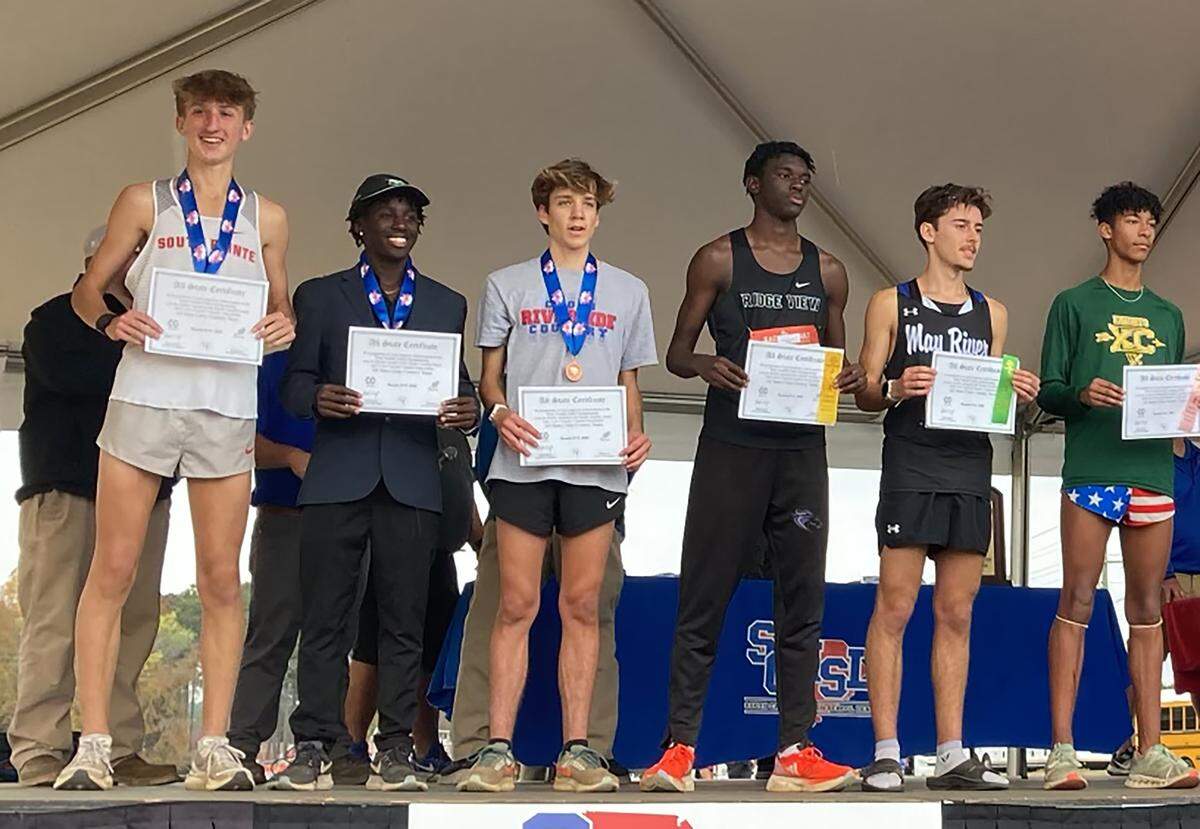South Pointe cross-country runner, left, holds a certificate after winning the state championship on Nov. 10.